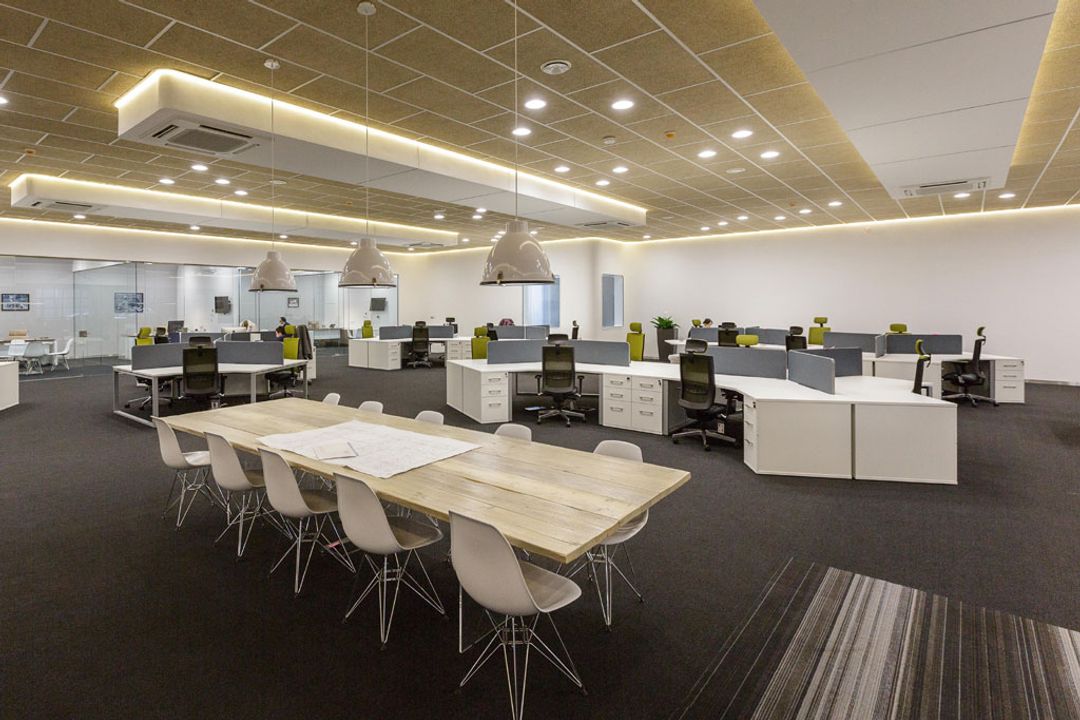 Main office area showing Vitra Eames side chairs
                    surrounding a bespoke natural wood meeting table and banks
                    of 180 degree workstations